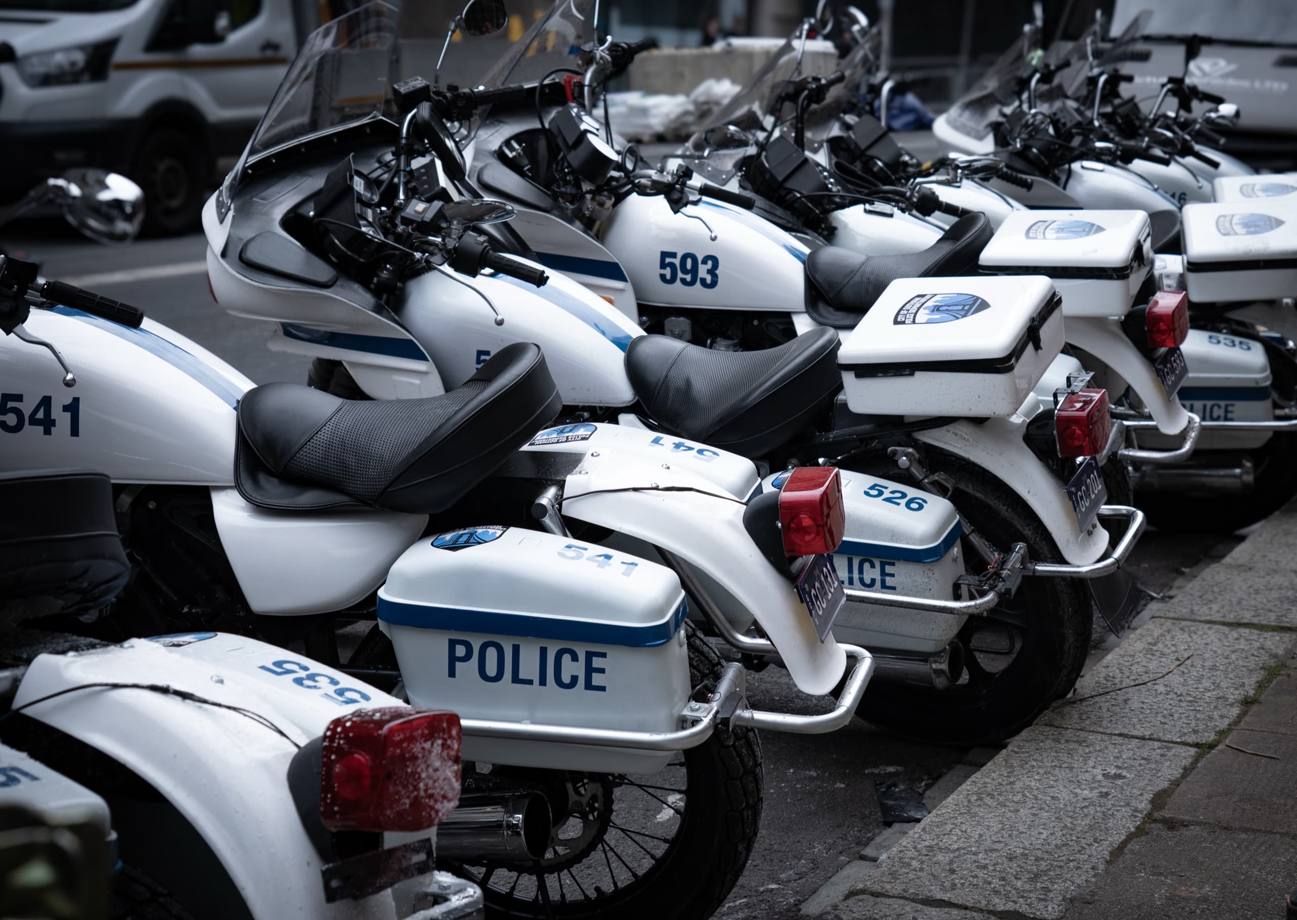 Police motorcycles parked along the side of a street in Glasgow, Scotland. The motorcycles are white and have the text GCPD on the side.