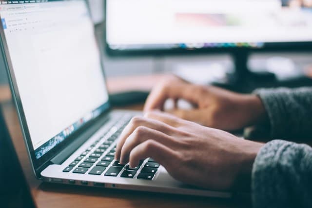 A person typing on a laptop keyboard